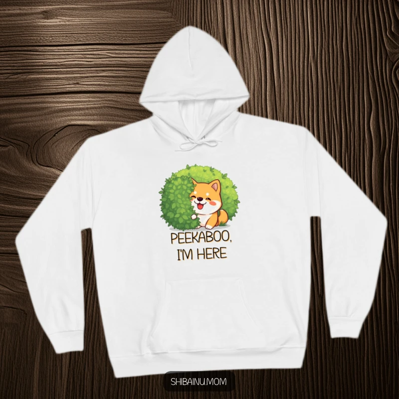 Funny Kawaii Shiba Inu hoodie featuring a giggling dog peeking mischievously from behind a bush. Warm and whimsical, an ideal funny gift.